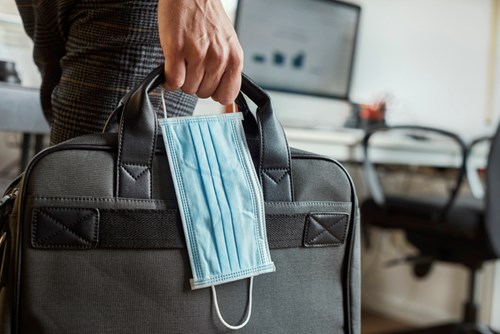 Broker carrying a briefcase and face mask.